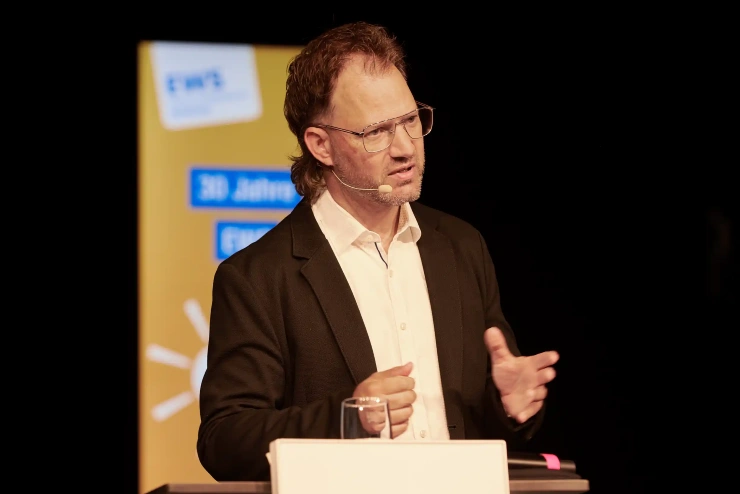 Armin Komenda, EWS-Vorstandsmitglied, steht an einem Podium und spricht.