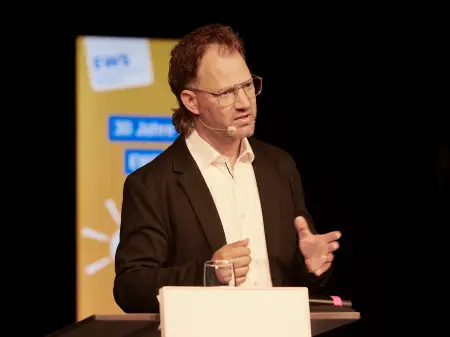 Armin Komenda, EWS-Vorstandsmitglied, steht an einem Podium und spricht.