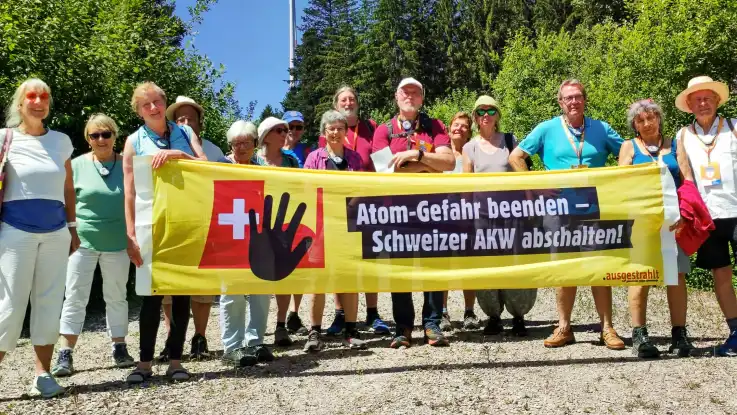 Ein Gruppe von Menschen in sommerlicher Kleidung hält ein Banner mit der Aufschrift: Atom-Gefahr beenden – Schweizer AKW abschalten!