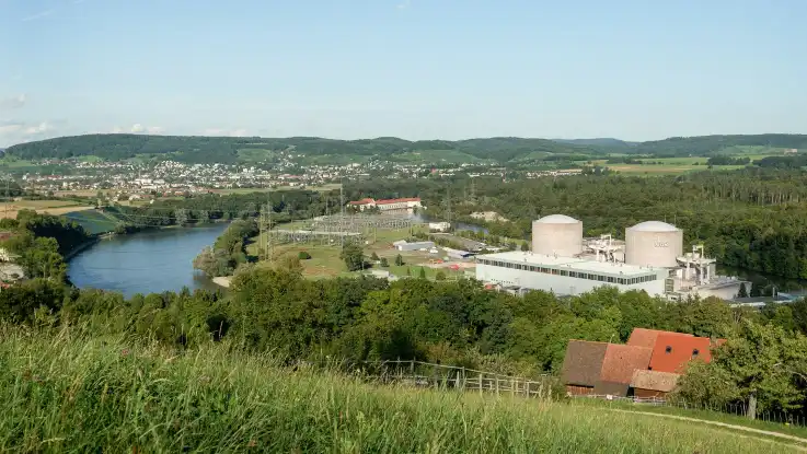Von einer Anhöhe aus erstreckt sich der Blick über ein AKW das entlang eines Flusses steht. 