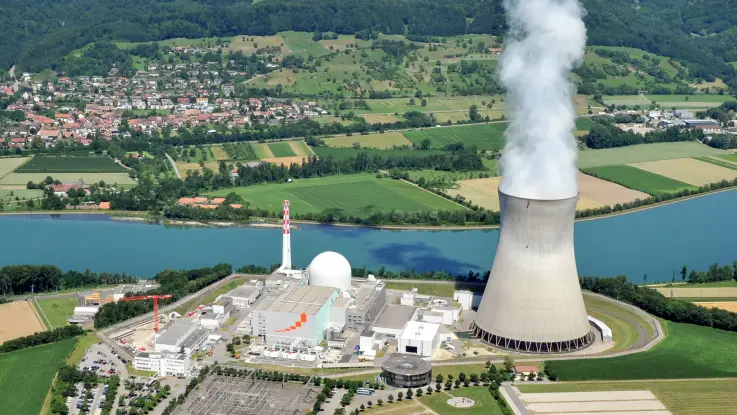 Luftbild des Atommeilers Leibstadt an einem Fluss in einer idyllischen Landschaft gelegen. Ein Dorf liegt in unmittelbarer Nähe.