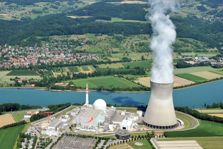 Luftbild des Atommeilers Leibstadt an einem Fluss in einer idyllischen Landschaft gelegen. Ein Dorf liegt in unmittelbarer Nähe.