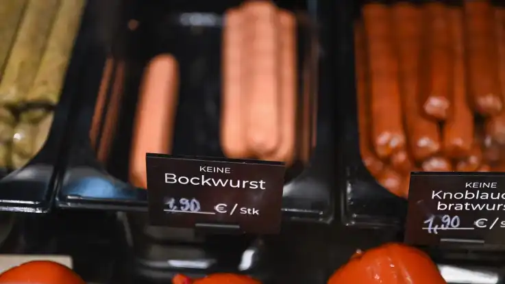 In einer Wursttheke liegen fleischfreie Würstchen aus, deren Behältnisse mit schwarzen Preisschildern versehen sind. 