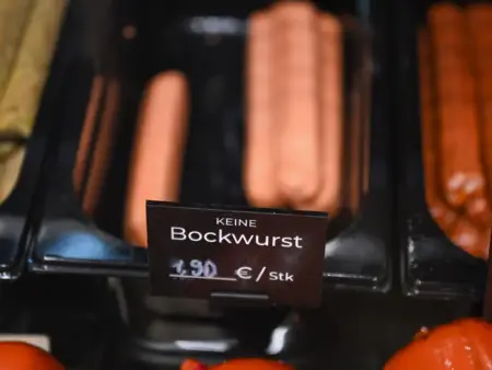 Ein Gruppe von Kindern spielt im Wassere einer steinigen Brandung – überall um sie herum befindet sich Plastikmüll. 