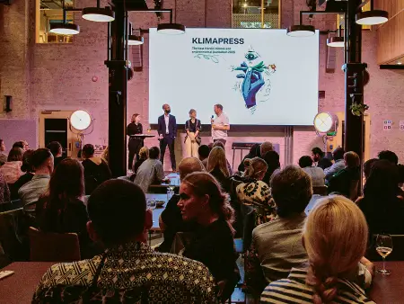 Eine Collage der berühmten „warming stripes“: Schrift liegt senkrecht auf den in Rot- und Blautönen gehaltenen Streifen.