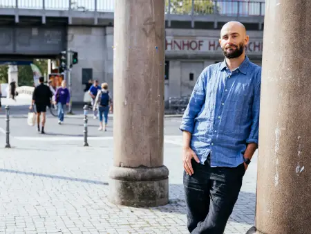 Philipp Staab lehnt lässig an einer Säule vor einer städtischen Straßenszene.