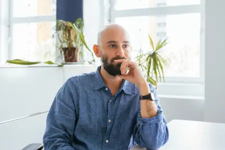 Philipp Staab sitzt an einem weißen Tisch, hält den Kopf in die Hand gestützt und schaut ins Leere.