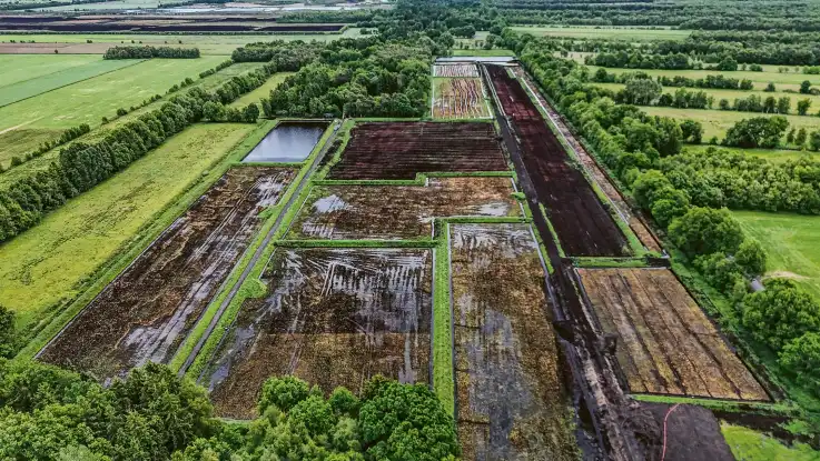 Aus der Vogelperspektive: Inmitten einer Kulturlandschaft liegen rechteckige Felder, auf denen sich Wasser staut. 
