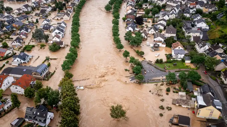 Die Luftaufnahme zeigt eine komplett überflutete Kleinstadt. Der ursprüngliche Flussverlauf ist nur noch an den Bäumen entlang des überspülten Ufers zu erahnen. 