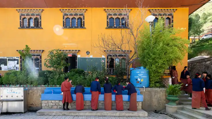 An einer weiteren Wasserstelle stehen ebenfalls Schüler:innen, die sich erfrischen oder ihre Flaschen auffüllen. 