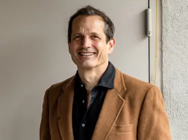 Ippolito steht vor einer Stahltür und lächelt in die Kamera.