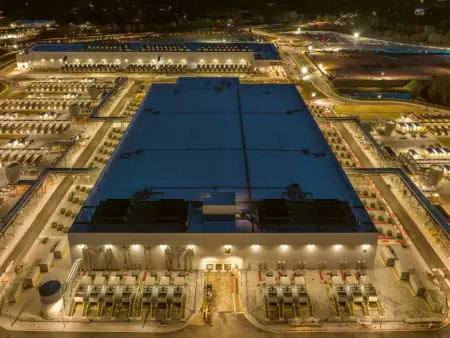 Ein Rechenzentrum von oben: die riesige Halle ist eingebettet in eine hell erleuchtete Infrastruktur. 