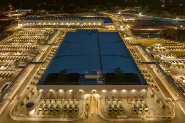 Ein Rechenzentrum von oben: die riesige Halle ist eingebettet in eine hell erleuchtete Infrastruktur.