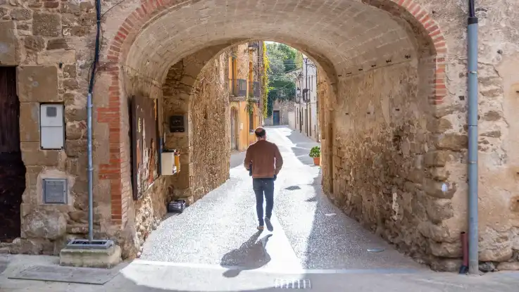 Ein Mann läuft durch eine menschenleere Gasse, die von historischen Steinhäusern gesäumt wird.