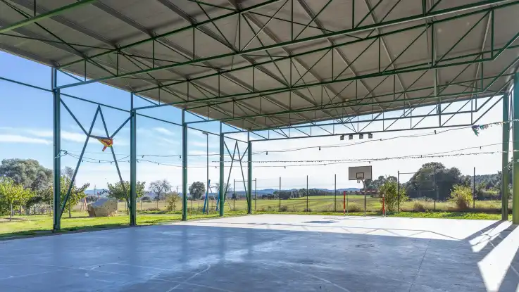  Ein überdachter Sportplatz mit Toren und Korbanlage im Freien. 