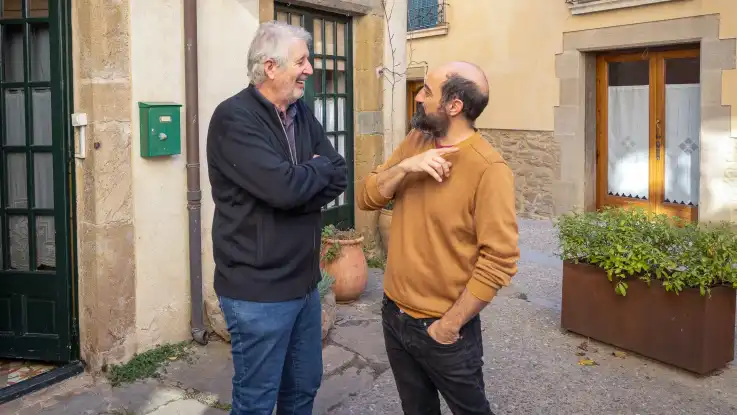 Zwei Männer stehen in einer Gasse und unterhalten sich angeregt.  