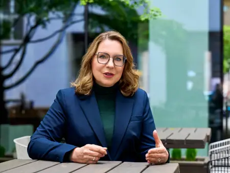 Claudia Kemfert sitzt an einem Holztisch in einer städtischen Umgebung und spricht mit einem gegenüber, das nicht im Bil dist.äölsd#fkd#gödlkh