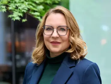 Frau Kemfert in einem Kopfportrait in einer grünen städtischen Umgebung.