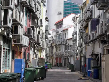 Vor den Häuserfassaden in einer schmalen, menschenleeren Gasse hängen hunderte Klimaanlagen. 