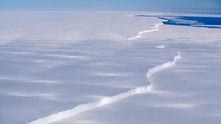 Ein Landschaftsaufnahme aus der Vogelperspektive zeigt eine schier endlose Eislandschaft, in der Mitte verläuft senkrecht eine Bruchkante bis zum Horizont.
