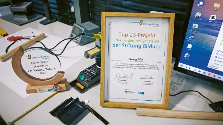Auf einem Schreibtisch steht einen gerahmte Urkunde, die den gewonnenen Förderpreis benennt.