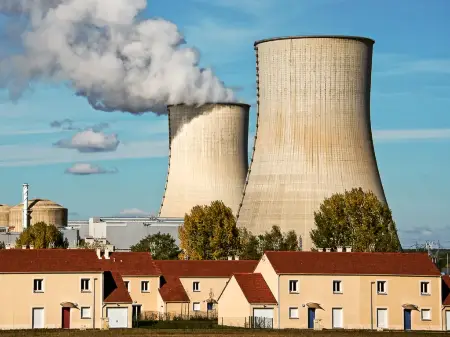 Kühltürme eines Atomkraftwerkes stehen unmittelbar hinter einer kleinen Reihenhaussiedlung. 